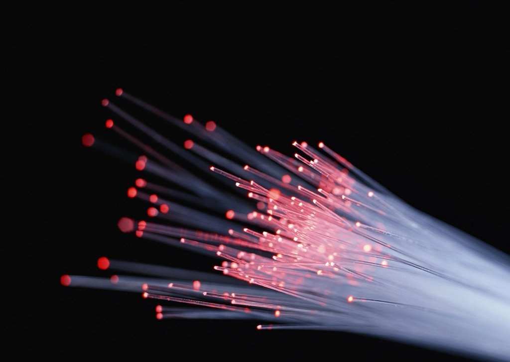 Strands of fibre optic cable glowing with pink light against a dark background